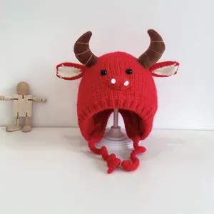 Cute red knit baby hat with ox horns, earflaps, and braided ties for winter warmth