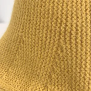 Macro shot of ginger yellow knit fabric detail showing soft wool texture and fine stitches