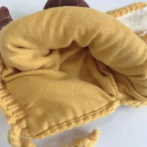 Close-up of baby knit hat showing yellow yarn exterior and soft cotton lining detail