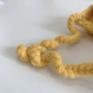 Macro shot of yellow thick-knit wool yarn showing the spiral crochet texture and details