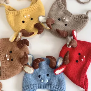 Close-up of five knitted baby beanies with cute horns in various colors on white background