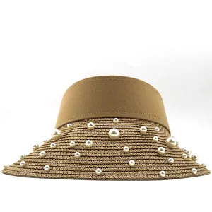Detailed view of hand-woven raffia straw sun hat brim with elegant white pearl decorations