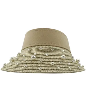 Detailed view of hand-stitched pearls on the brim of a khaki raffia straw sun hat