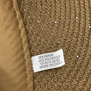Detailed view of woven straw sun hat material showing 55% paper and 45% polyester tag