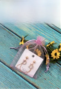 Detail of elegant D-letter earrings with crystals inside a pink organza drawstring gift bag