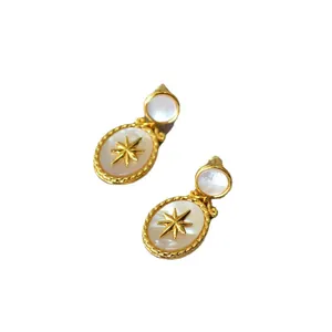 Vintage oval shell earrings with golden star and twisted border on white background