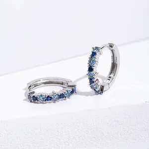 Macro detail of silver hoop earrings with gradient blue zircon and square gemstones