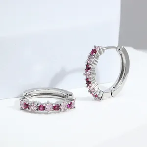 Detail of silver huggie earrings featuring alternating red and pink round zircons