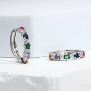 Macro detail of silver huggie hoop earrings with multi-color square-cut zircons
