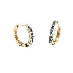 Gold huggie earrings featuring blue and white square zirconia stones in a prong setting