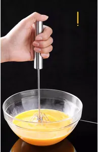Macro detail of a stainless steel semi-automatic whisk mixing egg yolks in a glass bowl