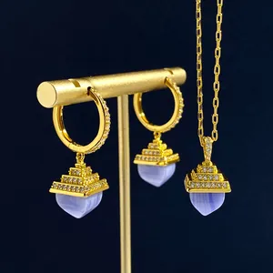 Detail view of gold pyramid earrings and necklace set with heart-shaped blue stones