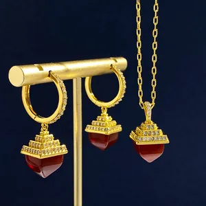 Golden jewelry set featuring geometric tiered pendants with red gemstones and crystals