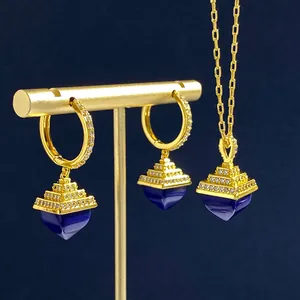Detail of luxury gold jewelry set with tiered pyramid pendants and blue stone inlay