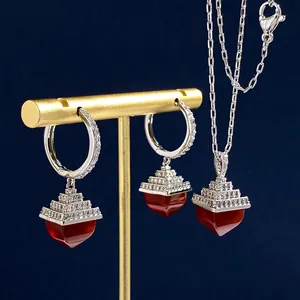 Detailed view of silver necklace and earrings set with red gemstones and pavé diamonds