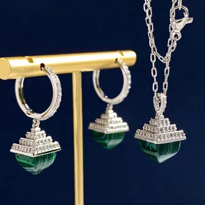 Detail of silver necklace and earrings set with green malachite and diamond accents