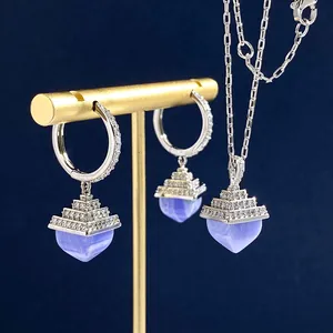 Silver pyramid earrings and necklace set with blue agate and pavé diamonds on a stand