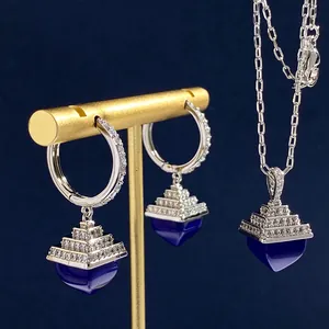 Macro view of silver tone jewelry set with diamond-encrusted blue pyramid pendants