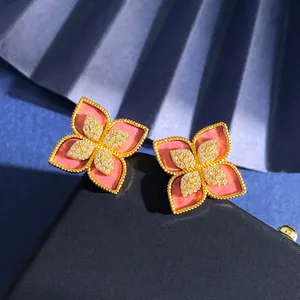 Dettaglio macro di orecchini a quadrifoglio in oro con petali rosa e centro in diamanti
