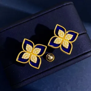 Dettaglio macro di orecchini a quadrifoglio in smalto blu e placcatura in oro 18 carati