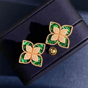 Dettaglio macro di orecchini a quadrifoglio in oro 18K con malachite e cristalli
