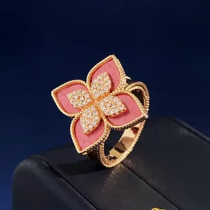 Macro detail of a gold flower ring with pink petals and sparkling white zircons