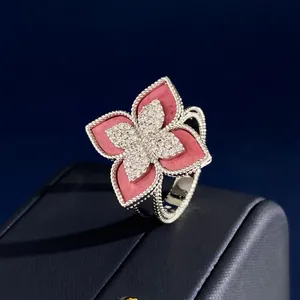 Macro shot of silver ring with red petals and diamond clover detail on dark base