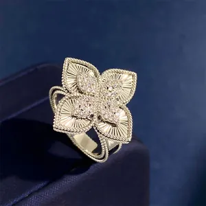 Luxe rhombic four-leaf clover flower ring with pavé diamonds on a blue velvet background