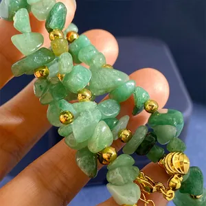 Bracciale di perline con avventurina verde e sfere dorate tenuto in mano da una donna