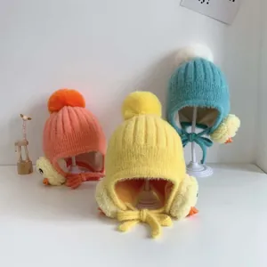 Detail von flauschigen Baby-Strickmützen mit Ohrenklappen, Bommeln und Enten-Motiv