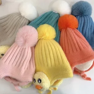 Nahaufnahme von Strickmützen für Kinder mit Bommeln und niedlichen 3D-Enten-Details