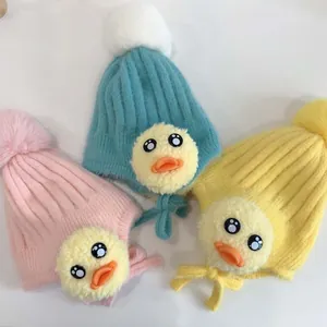 Detail von Baby-Strickmützen in Rosa, Blau und Gelb mit Plüsch-Ente und Pelz-Bommel