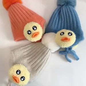 Detail von warm gestrickten Babymützen mit Entenfigur und weichen, flauschigen Bommeln