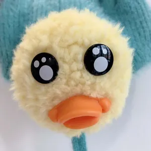 Detailaufnahme eines Plüschenten-Ornaments aus gelbem Kunstfell auf einer grünen Strickmütze