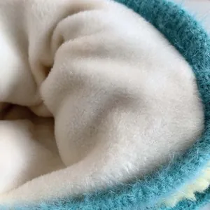 Nahaufnahme der Baby-Strickmütze mit warmem weißem Fleecefutter und blaugrüner Außenseite