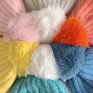 Detail von bunten Baby-Strickmützen mit flauschigen Kunstfell-Pompons in diversen Farben