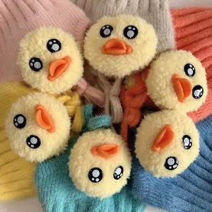 Detail einer weichen Baby-Strickmütze mit süßen 3D-Enten-Dekorationen und flauschigen Pompons