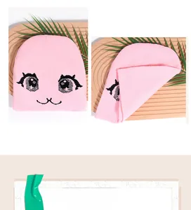 Detail of pink knitted beanie featuring cartoon anime eyes and cat mouth embroidery