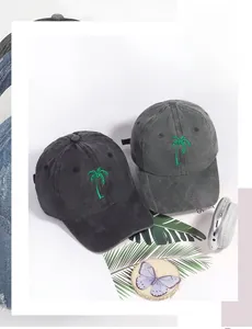 Detail of embroidered palm tree on washed cotton baseball caps in black and dark grey