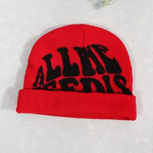 Red knit beanie with All We Need Is lettering and stylish wide cuff for winter warmth