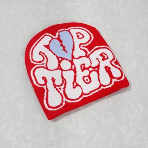 Close-up of red ribbed beanie featuring white TOP TIER text and blue broken heart embroidery