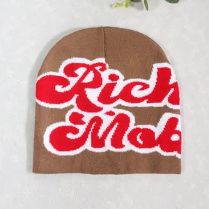 Close-up of jacquard knit beanie with red and white Rich Mob lettering on brown fabric