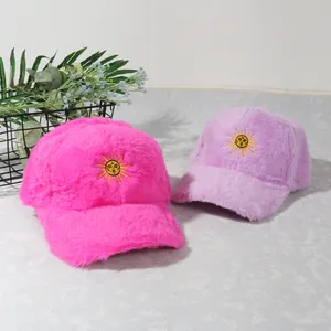 Détail de casquettes de baseball en peluche rose et violette avec broderie soleil