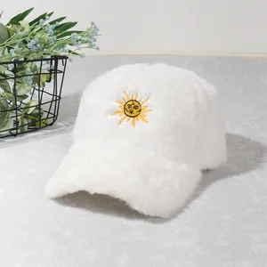Gros plan sur une casquette de baseball en peluche blanche avec broderie soleil jaune