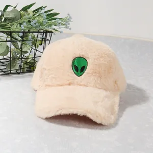 Close-up of beige plush baseball cap featuring a green alien head embroidery