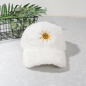 Gros plan d'une casquette en peluche blanche avec broderie soleil jaune sur tissu doux