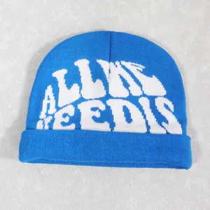 Detail view of navy blue knit beanie with white artistic letter jacquard pattern