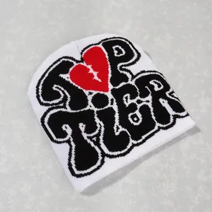 Detail of white Y2K beanie featuring black graffiti text and red stitched heart design