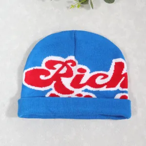 Detail of blue knit beanie featuring red Rich jacquard lettering and white outlines