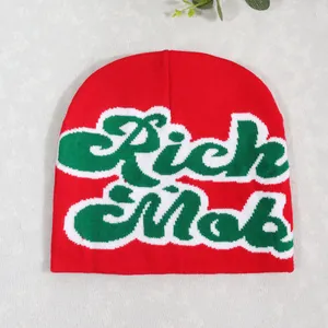 Close-up of red knit beanie featuring green and white Rich Mob jacquard embroidery